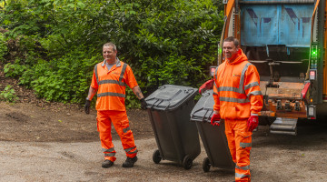 Two men collecting bins next to a bin lorry