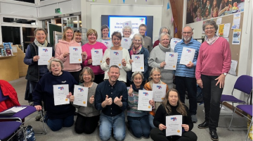 A group of people with their British Sign Language course certificates in Aldeburgh Library