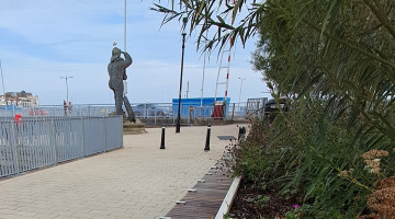An image of the pocket park in Lowestoft featuring a statue and a large planter with seating
