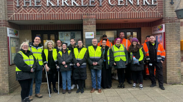 Group of people in hi-vis jackets with litter picking equipment