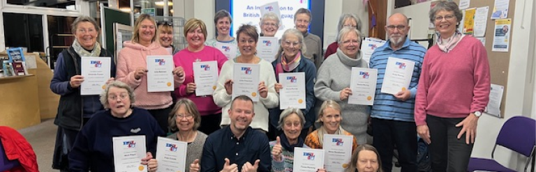 A group of people with their British Sign Language course certificates in Aldeburgh Library