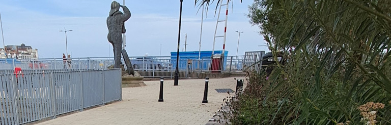 An image of the pocket park in Lowestoft featuring a statue and a large planter with seating