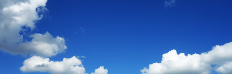 blue sky with fluffy white clouds and a field of grass