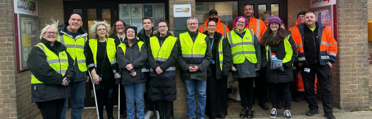 Group of people in hi-vis jackets with litter picking equipment