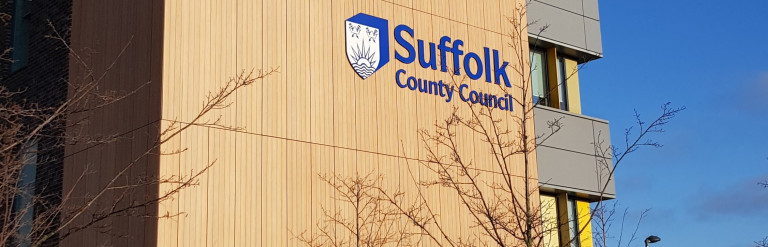 A tall office building among trees against a blue sky